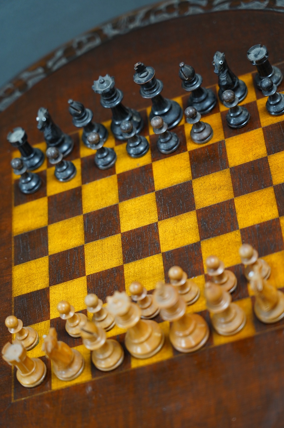 A Victorian carved walnut games table and chess pieces, table 74cm tall, king 6cm tall. Condition - good